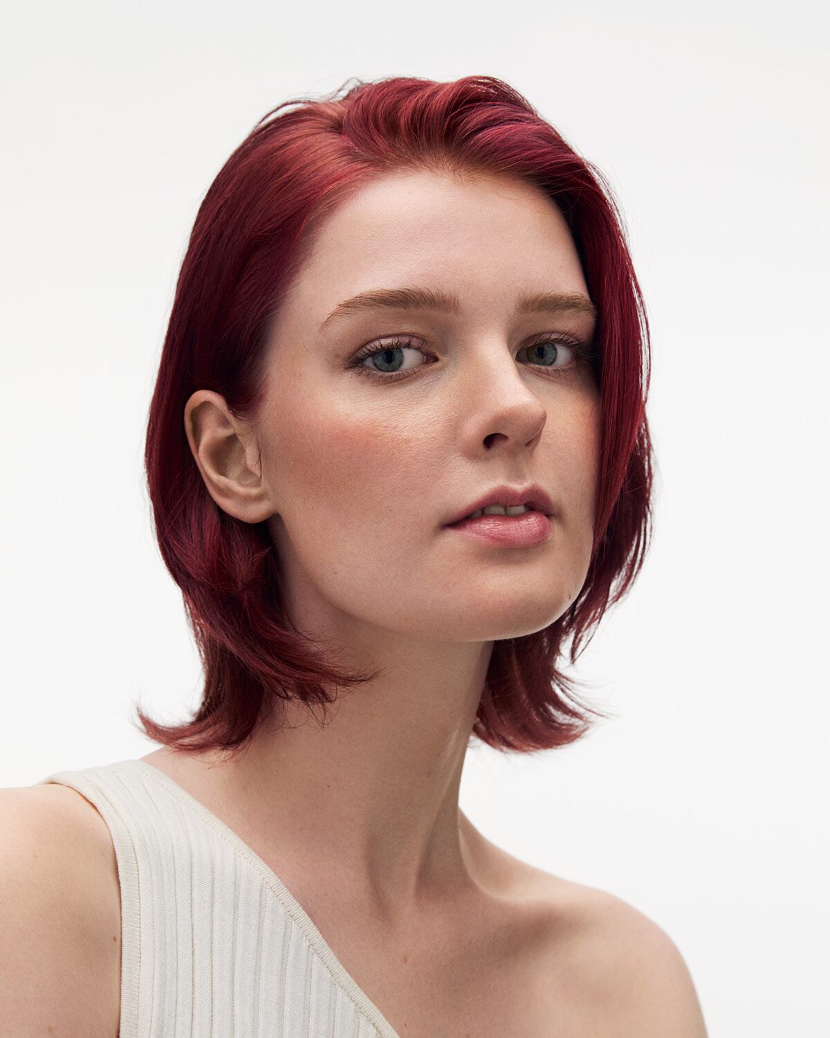 Woman with red hair wearing a white top on a white background