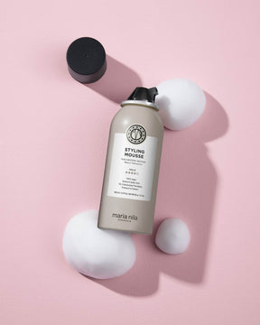 Marina Nila styling mousse bottle on a pink background