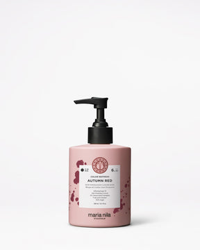 Pink hair care product bottle with black pump on a white background