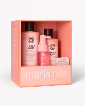 Maria Nila haircare gift set in a peach-colored box, containing two Mirror Gloss bottles, a Gloss Coat pump bottle, and a free mini gloss coat card, on a white background.