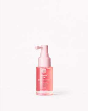 Small pink spray bottle labeled Gloss Coat Travel with white text on a clear container.