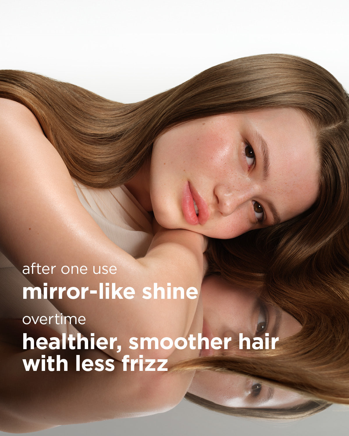 Glossy hair mask tube beside a reflective mirror showcasing long, smooth, shiny brown hair.