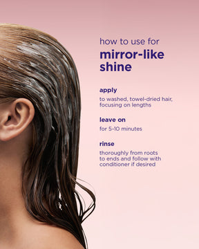 Wet hair coated with shiny, smooth Mirror Gloss Mask on dark brown strands against pale pink background.