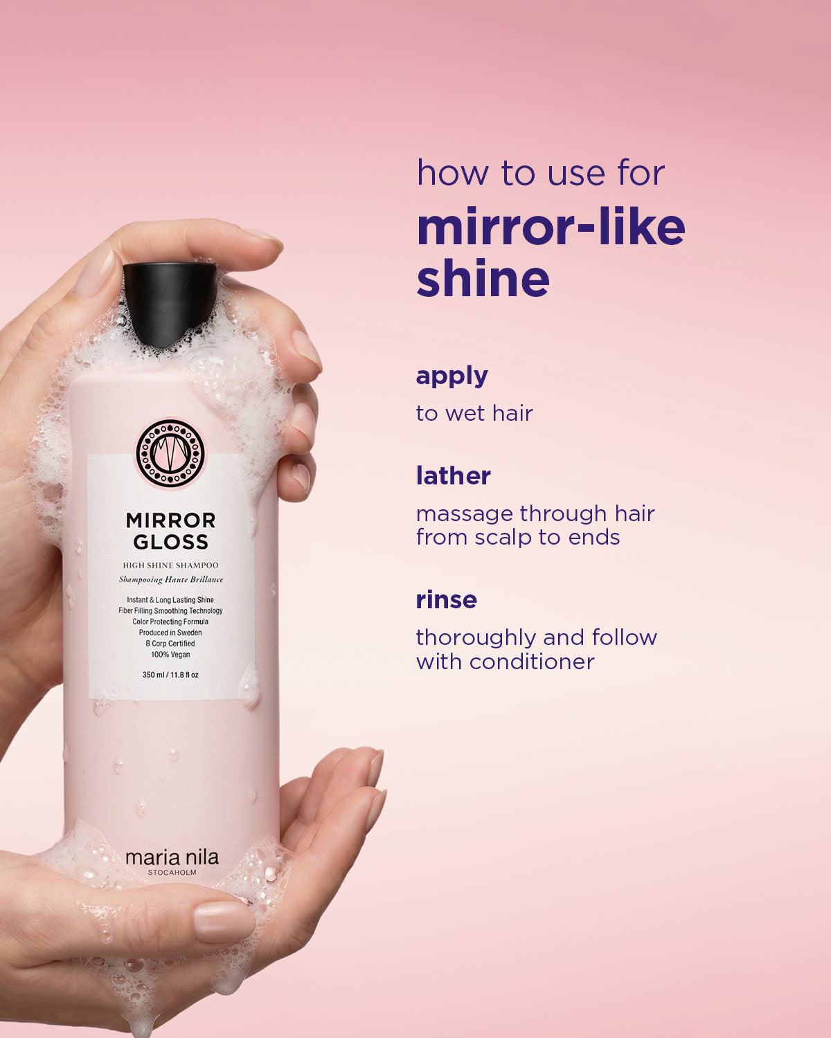 Tall frosted white shampoo bottle with black cap and white label held by two hands against a pink background with mirror.