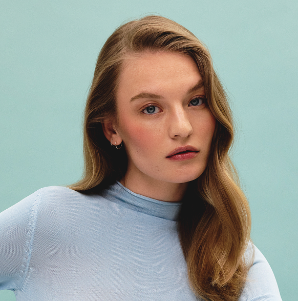 Model with dark blonde hair against  blue background