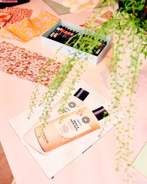 Head & Hair Heal Shampoo and Conditioner packaging with floral design on a pink surface with green leaves.