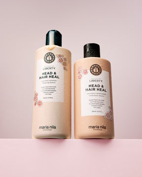 Two bottles of Maria Nila exclusively for Liberty Head & Hair Heal shampoo and conditioner on a pink background