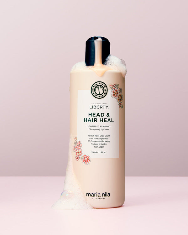 Bottle of Maria Nila Liberty Head & Hair Heal shampoo on a light pink background