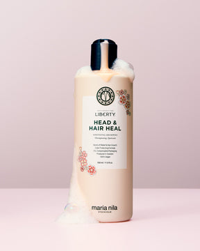 Bottle of Maria Nila Liberty Head & Hair Heal shampoo on a light pink background