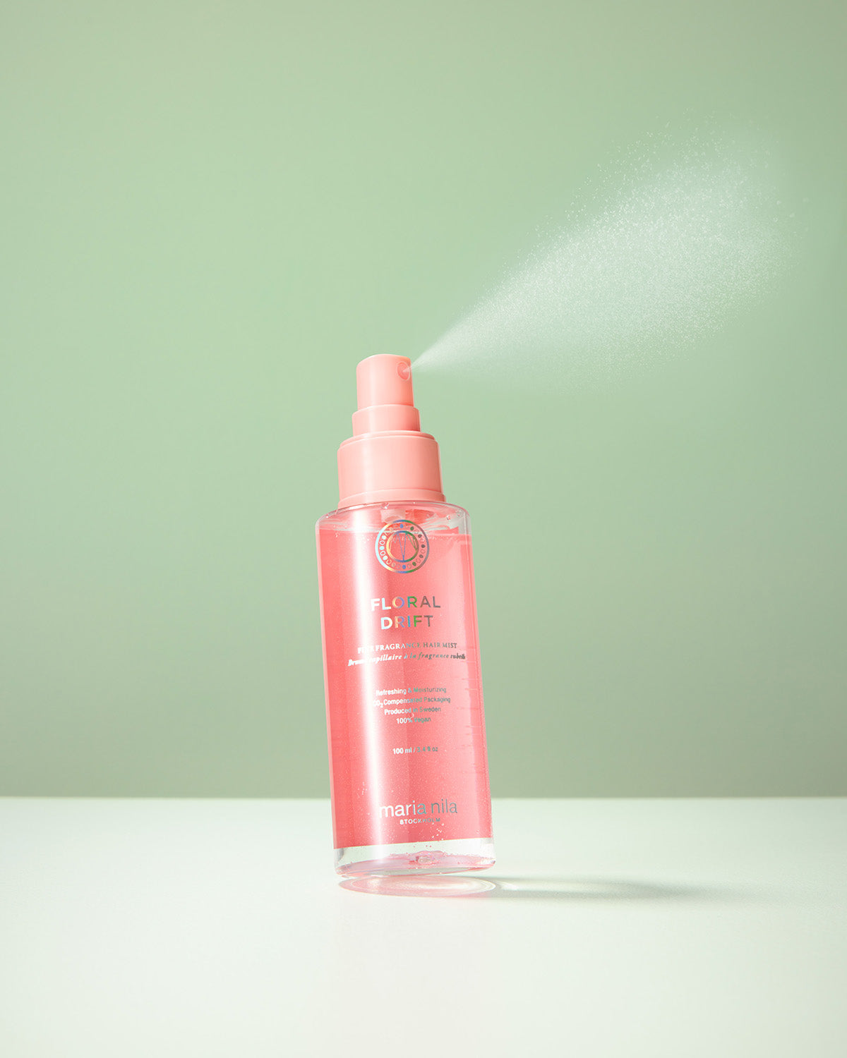 Pink spray bottle with Maria Nila Floral Drift hair mist a light green background