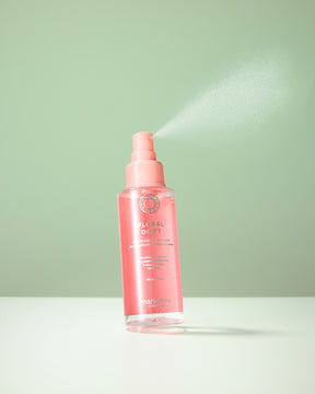Pink spray bottle with Maria Nila Floral Drift hair mist a light green background